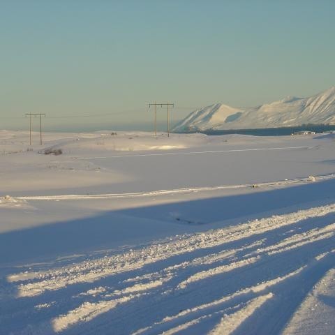 Tjörnin ísilögð og þakin snjó.